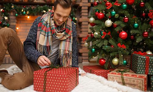 Muž ve svetru s barevnou šálou s dárkem