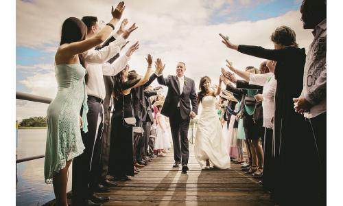 Svadobný pár v obleku a šatách so svadobnými hosťami